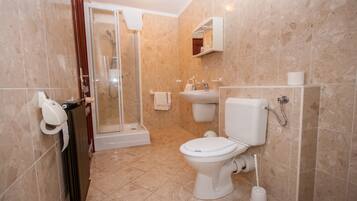 Un baño con inodoro, lavabo y ducha.