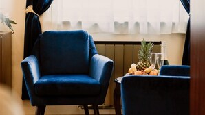 A room with a blue armchair and a small table with fruits and drinks. - Korona Pension Restaurant (Hévíz)