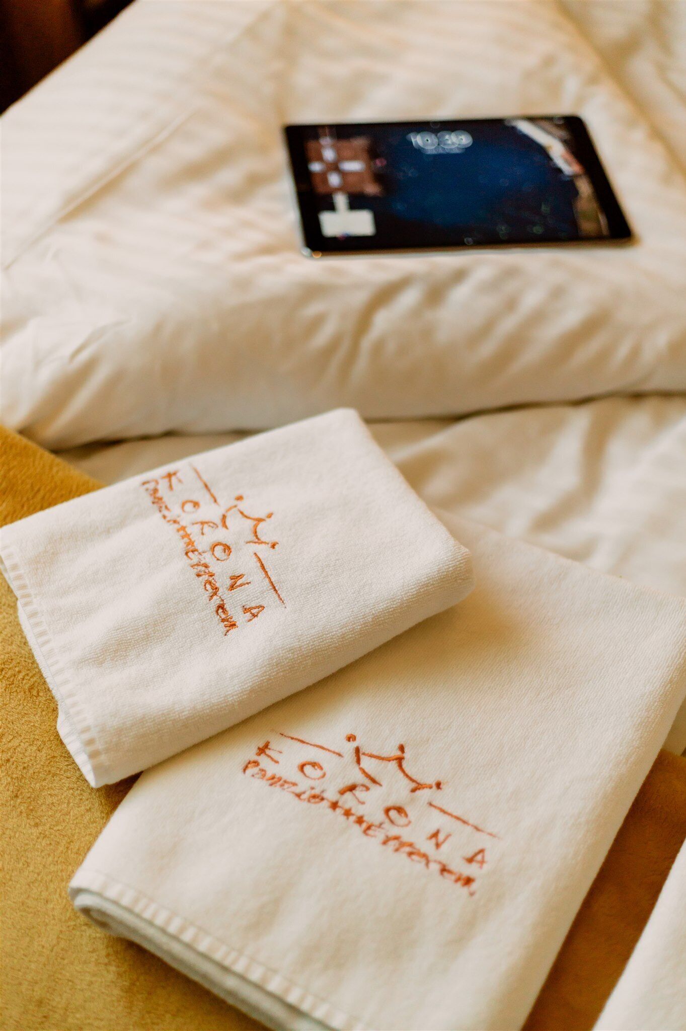 Una toalla blanca doblada con cuidado con texto bordado sobre una cama.