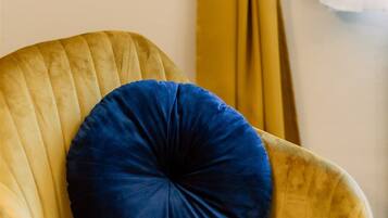 Una silla con un cojín azul y una cortina amarilla atada.