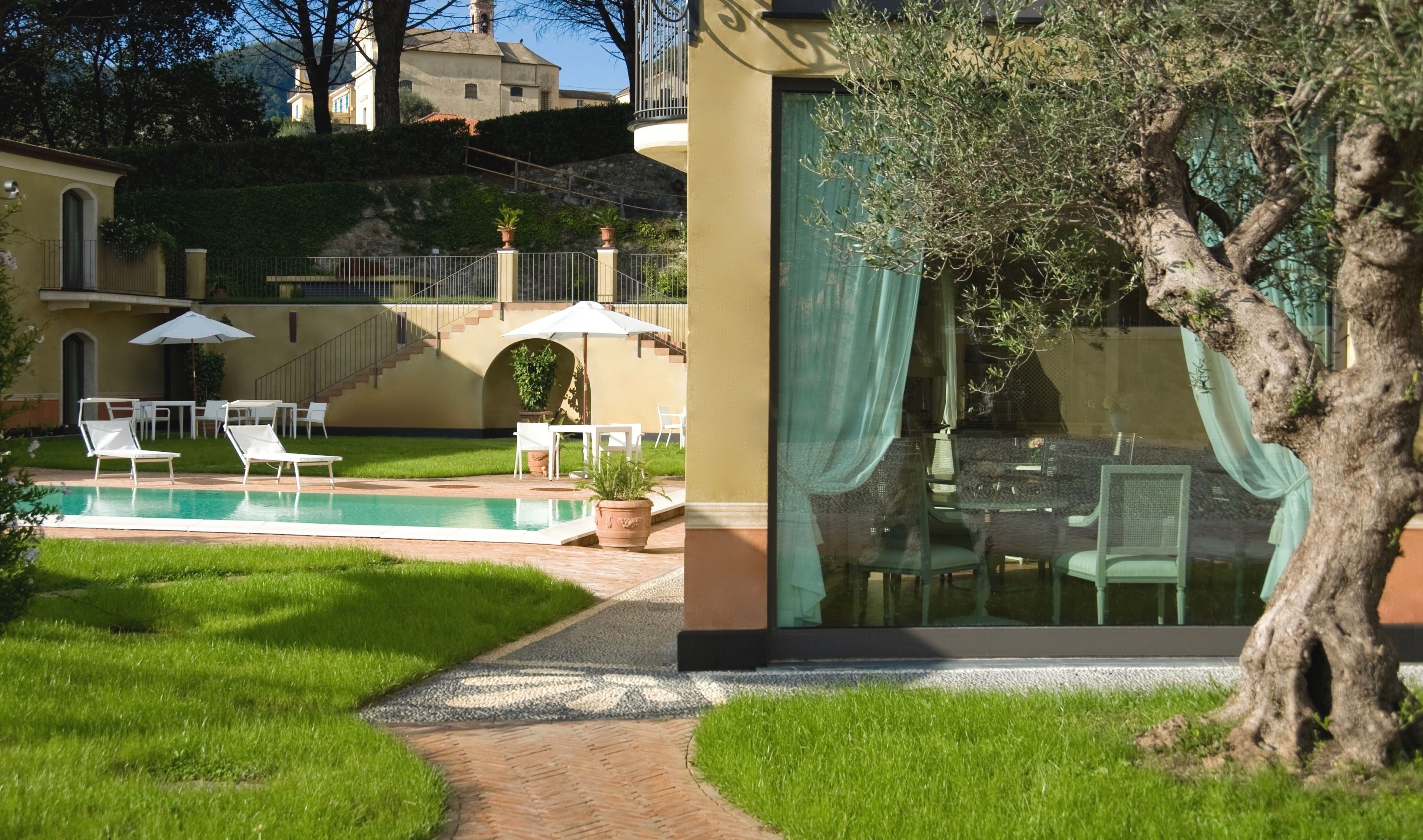 Un área de piscina con sillones de descanso y un comedor con paredes de vidrio.