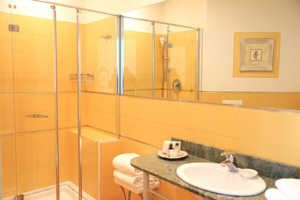 A bathroom with a glass-enclosed shower, a sink with a marble countertop, and a mirror. - Villa Agnese (Sestri Levante)