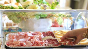Un bufé con diferentes opciones de comida, incluyendo carnes y quesos en rodajas.