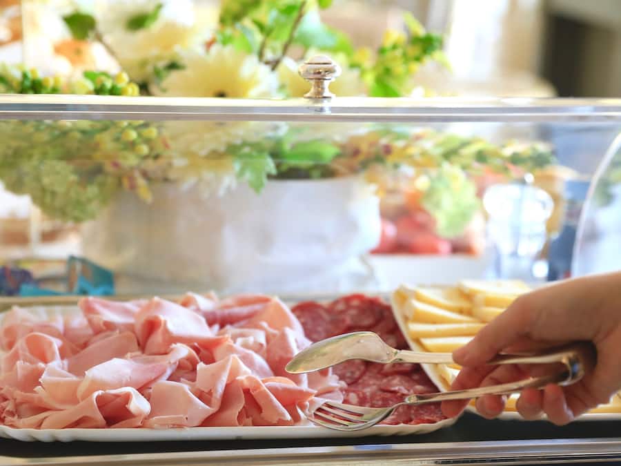 Un bufé con diferentes opciones de comida, incluyendo carnes y quesos en rodajas.