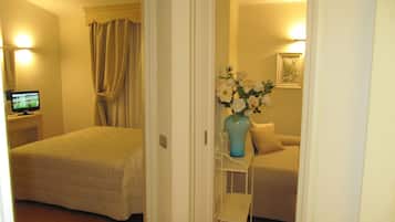 Une chambre d’hôtel avec un lit, une télévision, un vase de fleurs et un canapé.