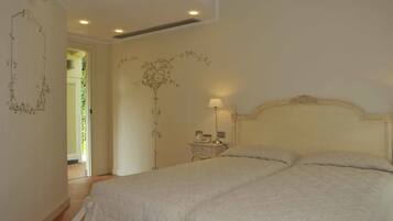 Un dormitorio con una cama grande, una mesita de noche con lámpara y una pared decorada con motivos florales.