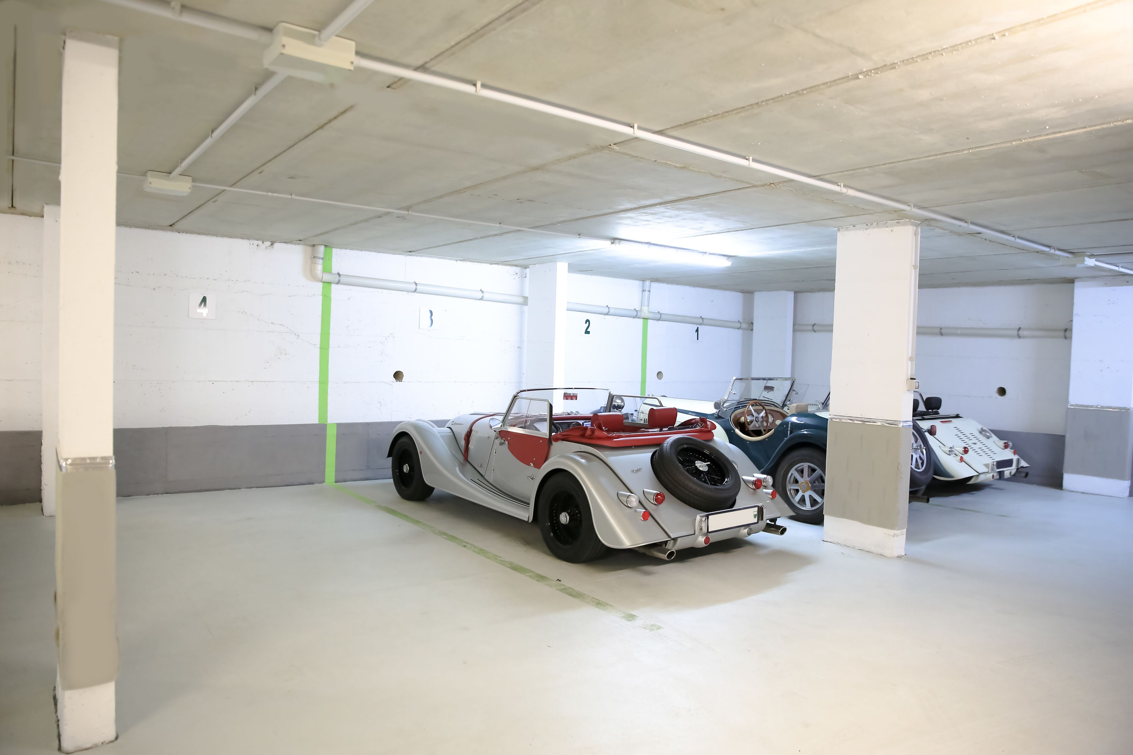 A parking garage with white walls and concrete pillars.