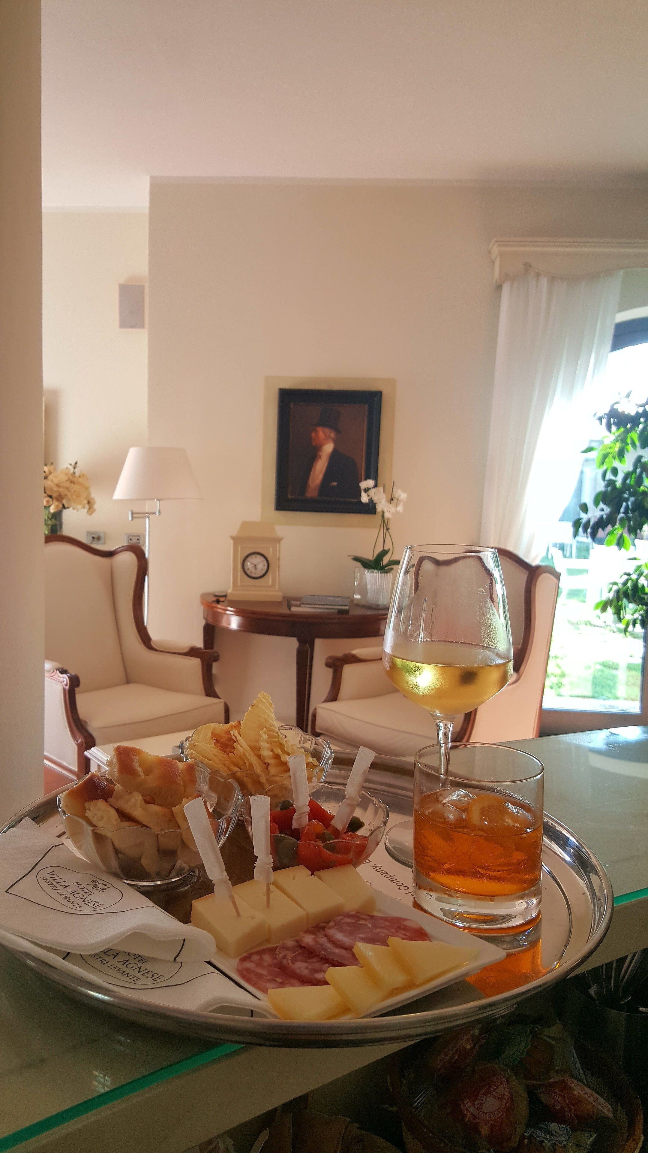 Un vassoio con formaggio, cracker e un bicchiere di vino in una camera d'albergo.
