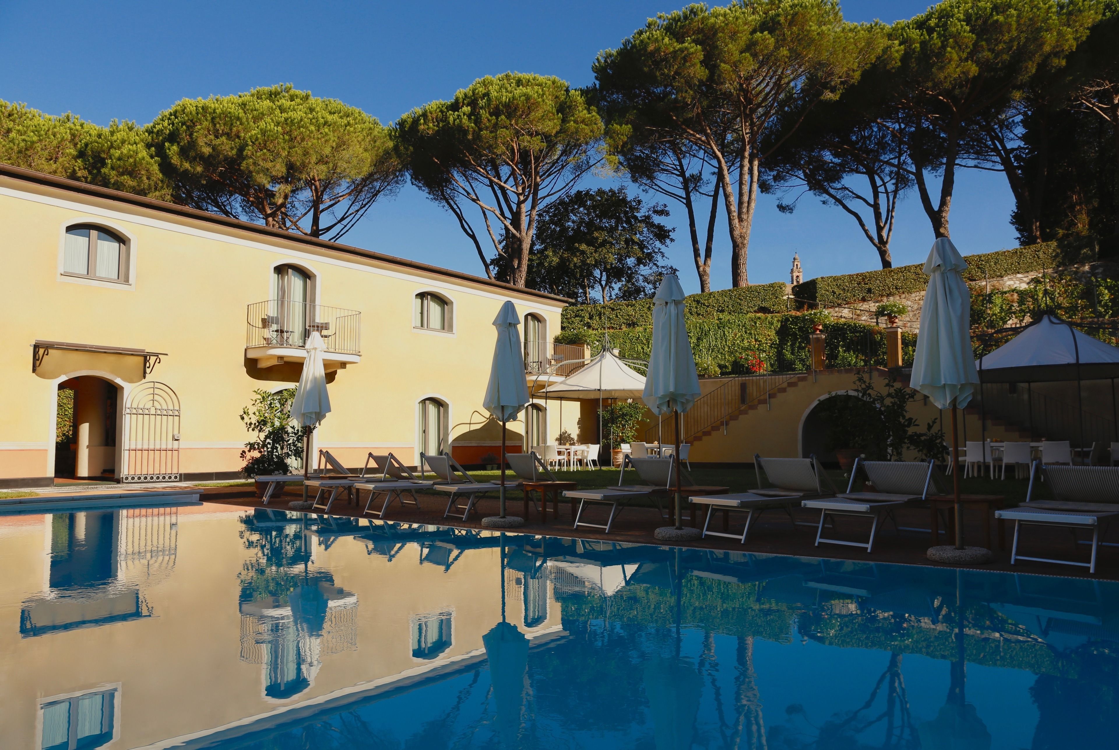 Una piscina al aire libre, sombrillas, sillones reclinables de piscina