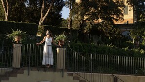 A woman in a white dress standing on a bridge with a staircase leading to a building. - Villa Agnese (Sestri Levante)