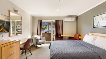 A hotel room with a bed, a desk, a chair, a dresser, a window with curtains, and a painting on the wall.