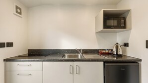 A compact kitchen with a built-in microwave, a sink, and a dishwasher. - Queenstown Motel Apartments (Queenstown)
