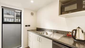 A modern kitchen with a stainless steel sink, a microwave, and a kettle on the countertop.
