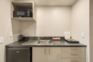 A compact kitchen with a built-in microwave, stainless steel sink, and a dishwasher. - Queenstown Motel Apartments (Queenstown)