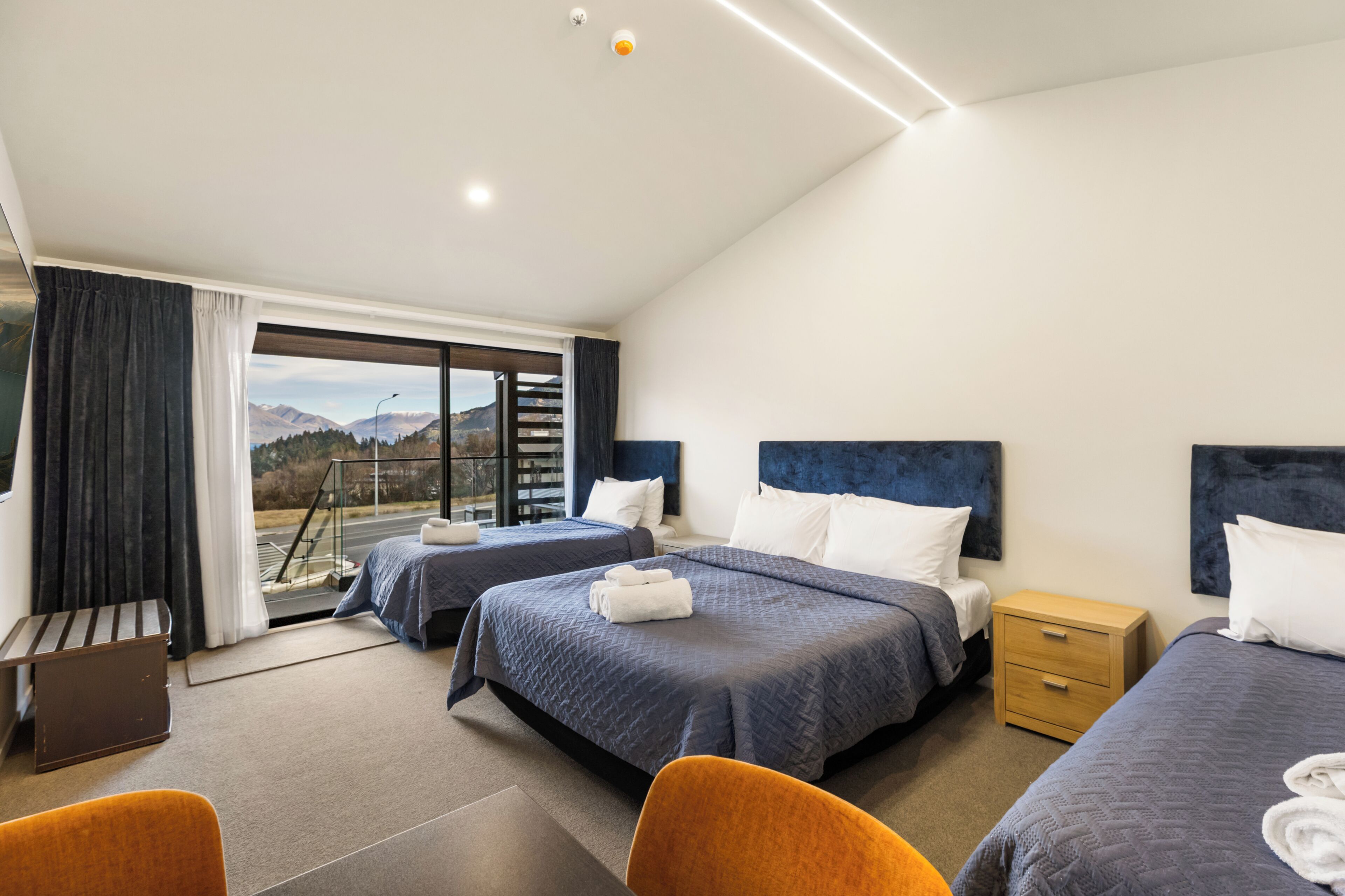 A hotel room with two beds, a desk, and a view of the mountains.