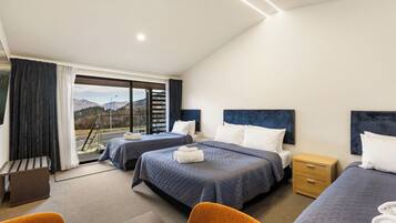 A hotel room with two beds, a desk, and a view of the mountains.