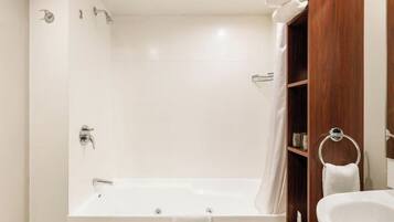 A bathroom with a bathtub, a sink, and a wooden vanity.