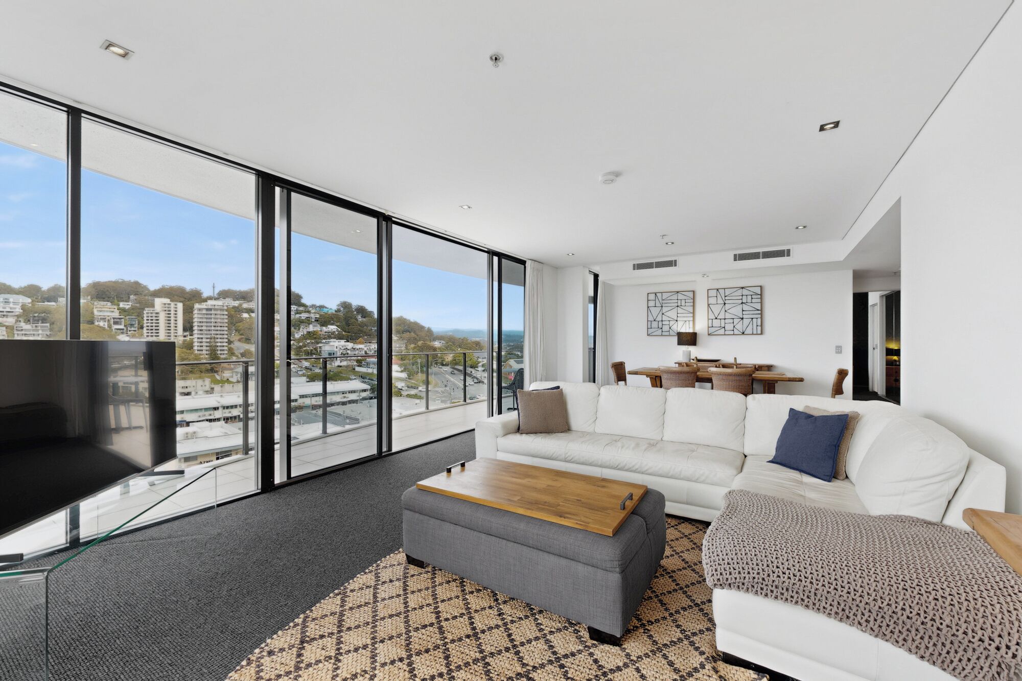 A modern living room with a large window, a sofa set, a coffee table, and a television.