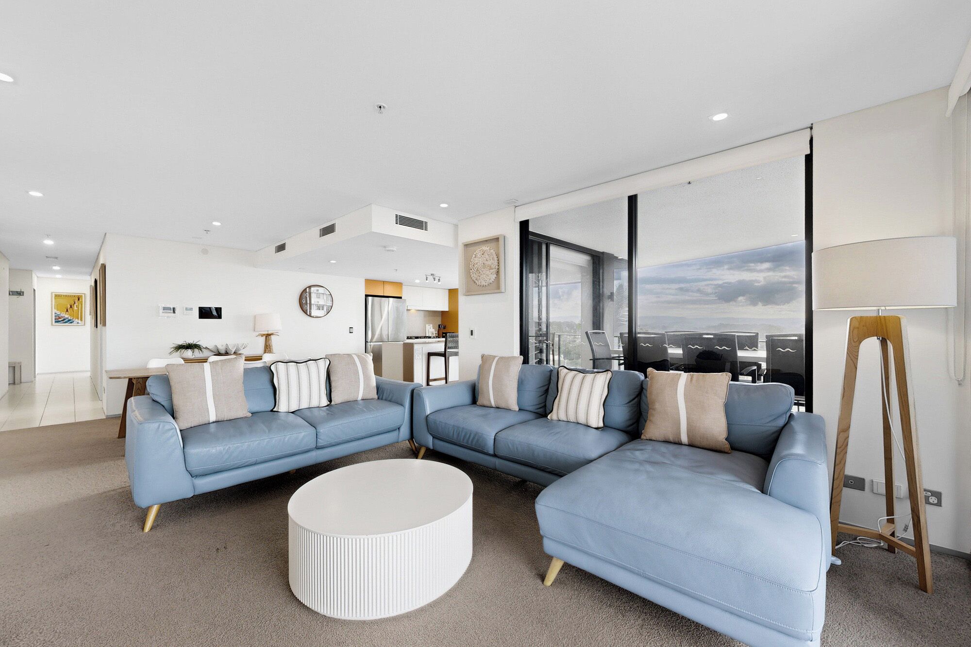 A modern living room with a sectional sofa, a round coffee table, and a view of the city through large windows.