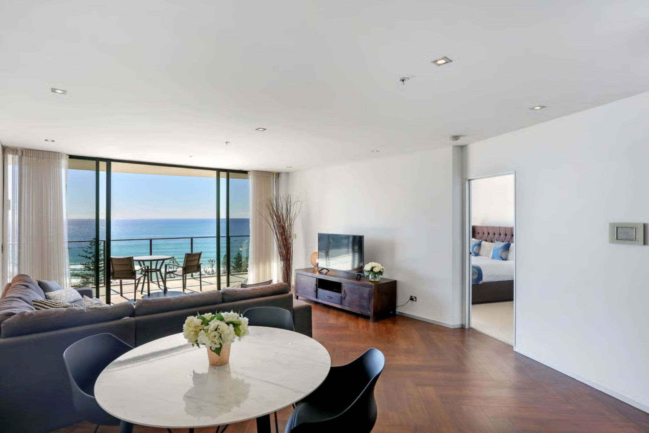 A modern hotel room with a balcony, a dining area, and a bedroom.