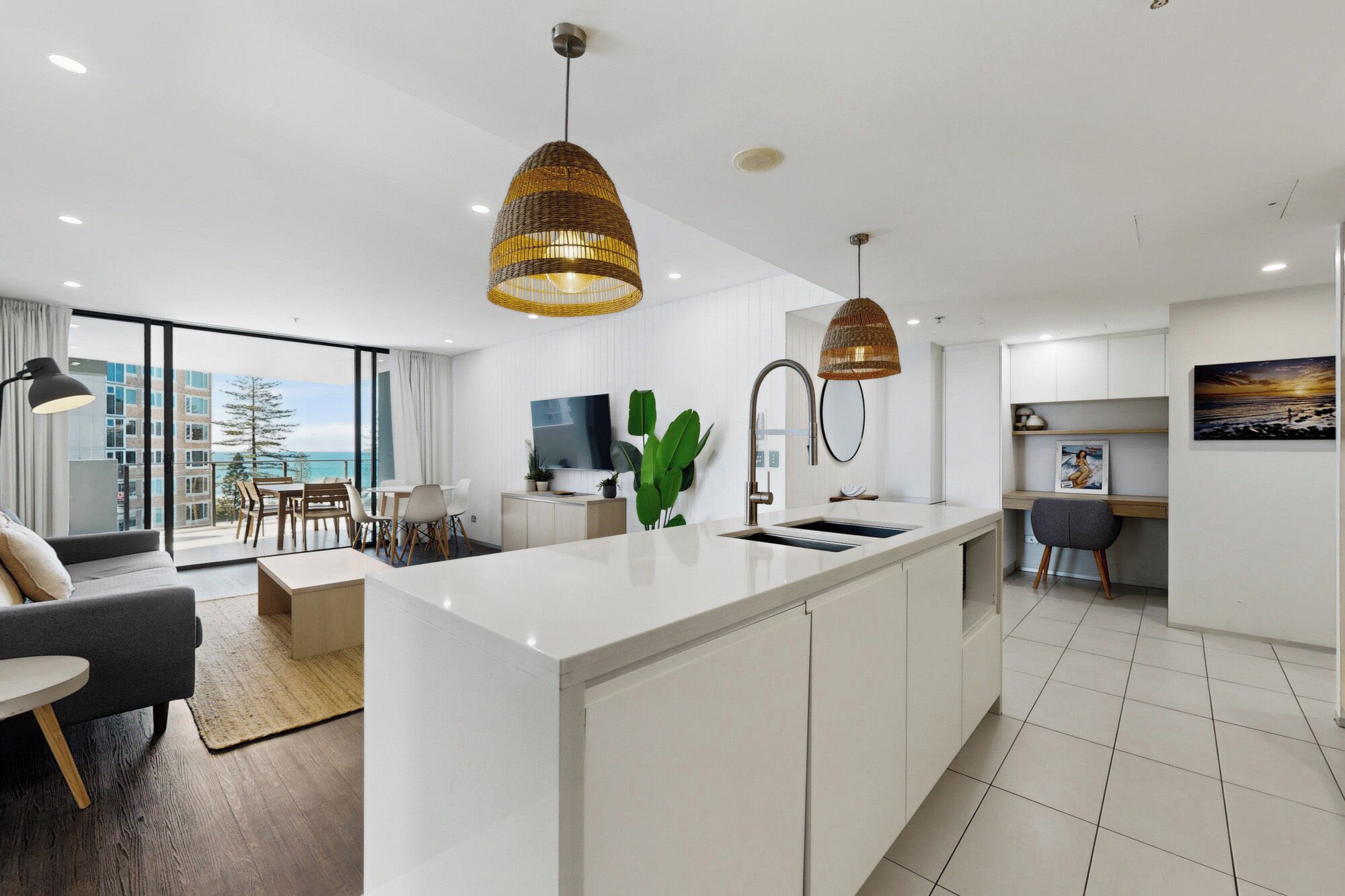 A modern kitchen with a central island, pendant lights, and a view to the outside.