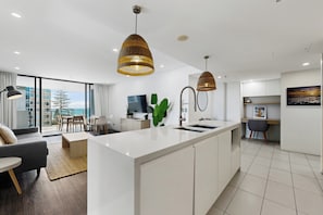 Cocina moderna con isla central, luces colgantes y vistas al exterior.