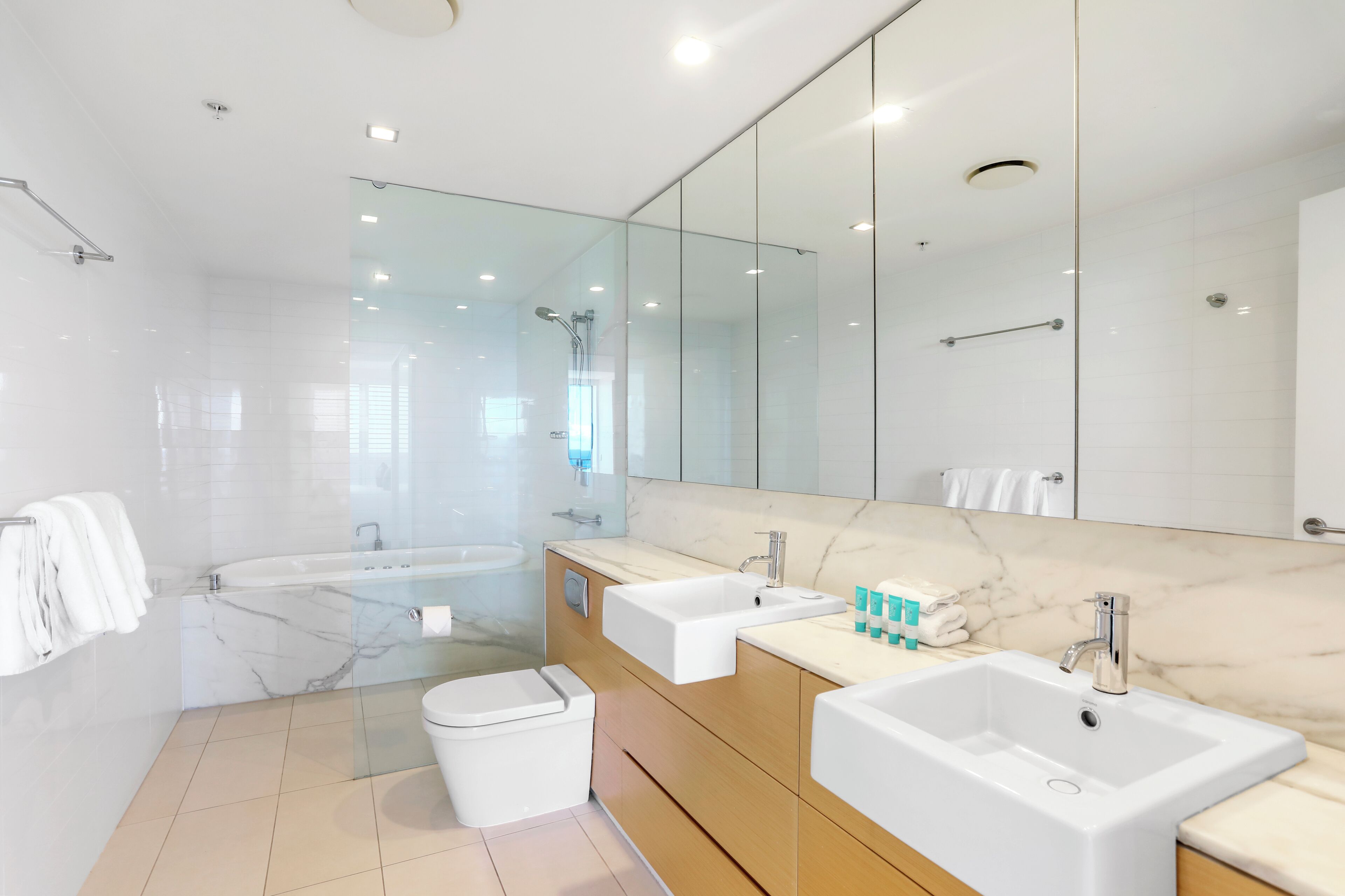 A modern bathroom with a glass-enclosed shower, a large mirror, and two sinks.