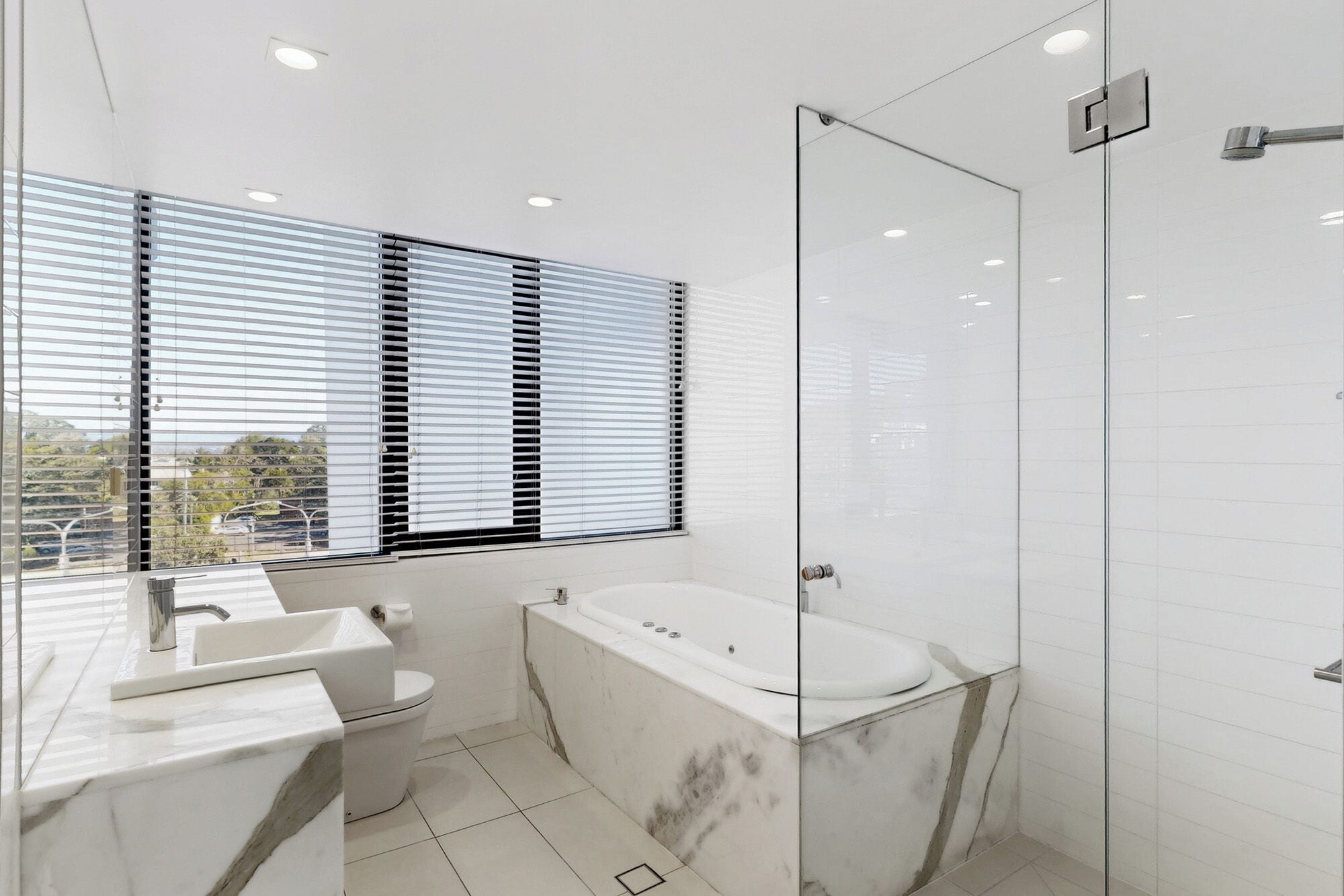 Ein modernes Badezimmer mit Duschkabine aus Glas, einer Badewanne und einer Toilette.