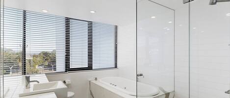 Ein modernes Badezimmer mit Duschkabine aus Glas, einer Badewanne und einer Toilette.