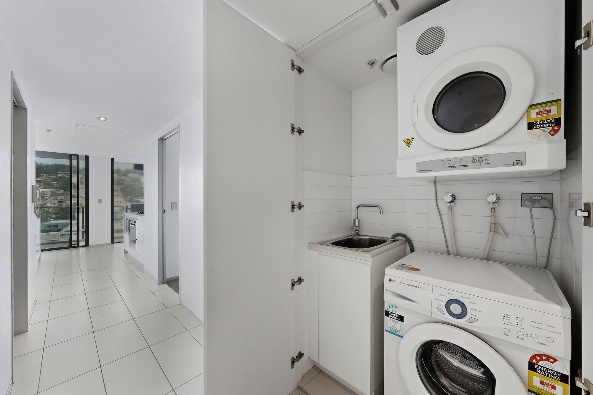 A modern laundry room with a washing machine, dryer, and a small sink.