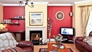A living room with a fireplace, a television, and two leather sofas.