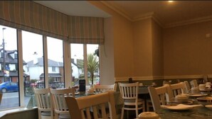 A restaurant with a large window, wooden chairs, and a glass table with a polka dot pattern. - St Judes Lodge (Galway)