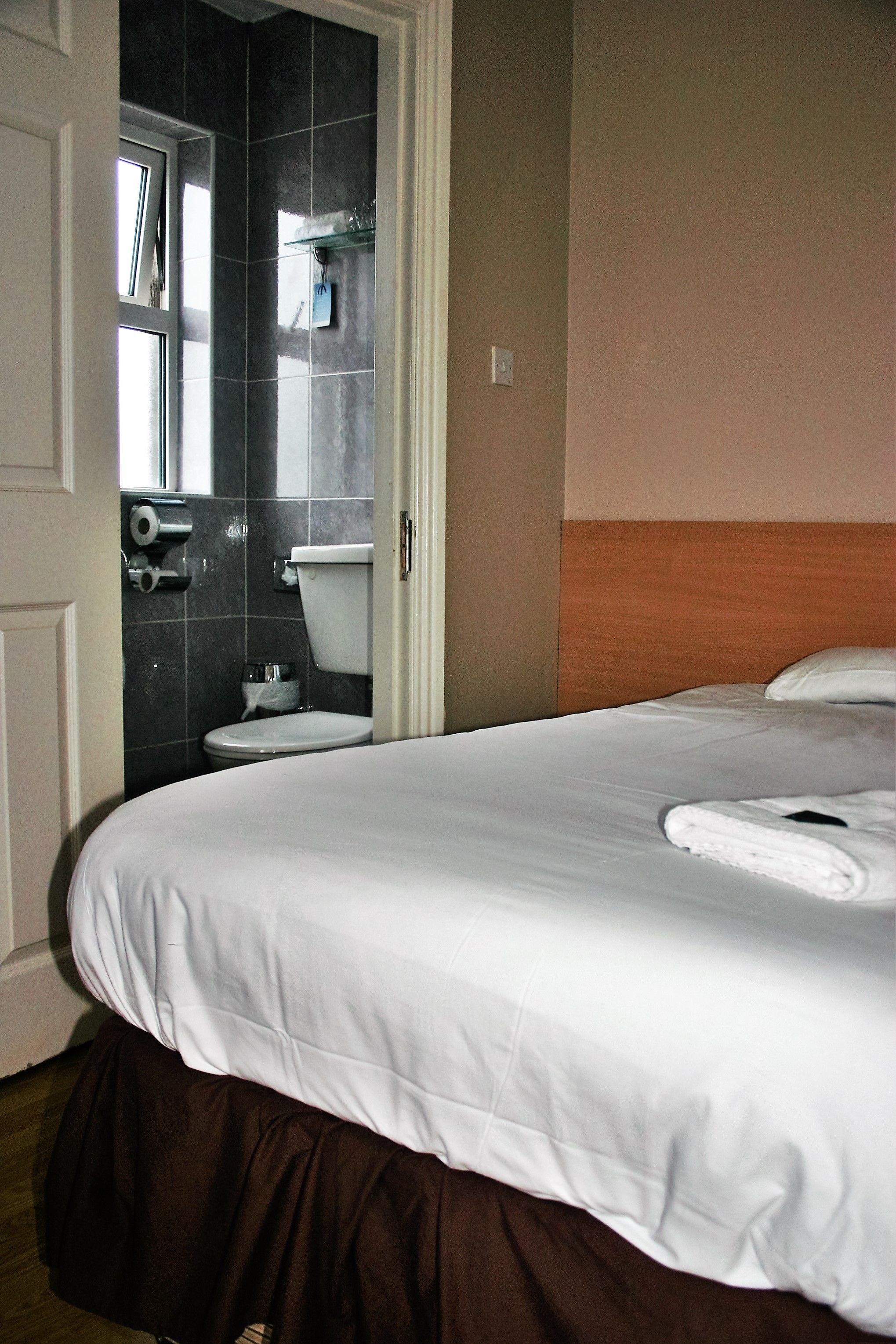 A hotel room with a bed, a bathroom with a toilet, and a window.