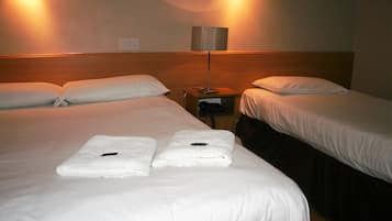 A hotel room with two beds, a nightstand, and a lamp.