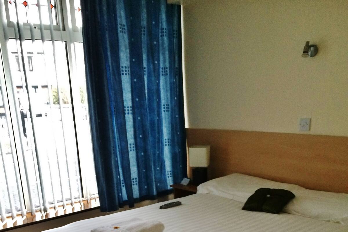 A neatly made bed with towels, a remote control, and a pillow on a wooden headboard.