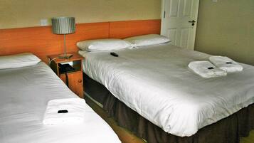 A hotel room with two beds, a nightstand, a lamp, and a door.
