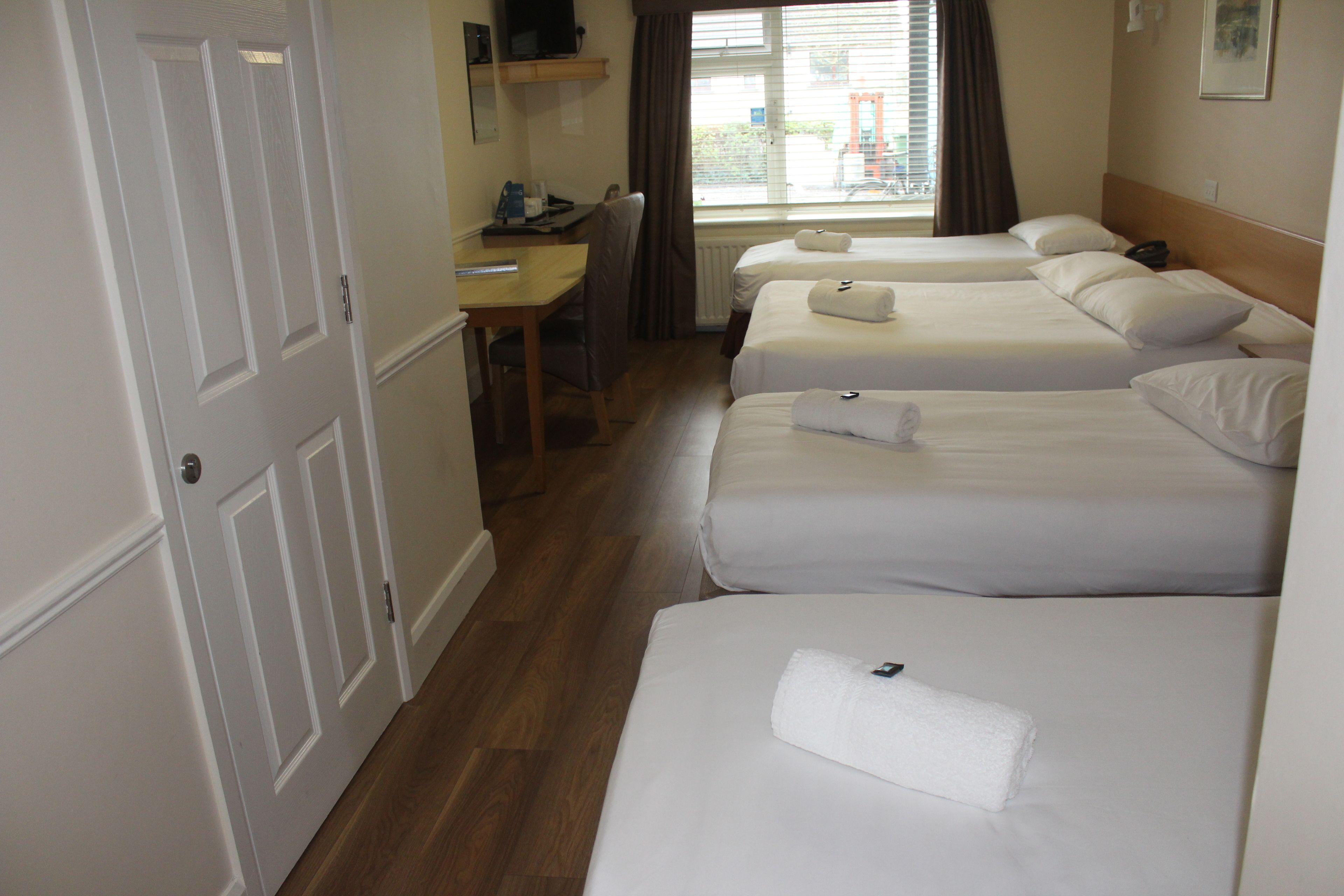 Ein Hotelzimmer mit zwei Betten, einem Schreibtisch und einem Stuhl.