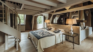 Un dormitorio con una cama grande, una mesita de noche, una lámpara, un sofá y una escalera.