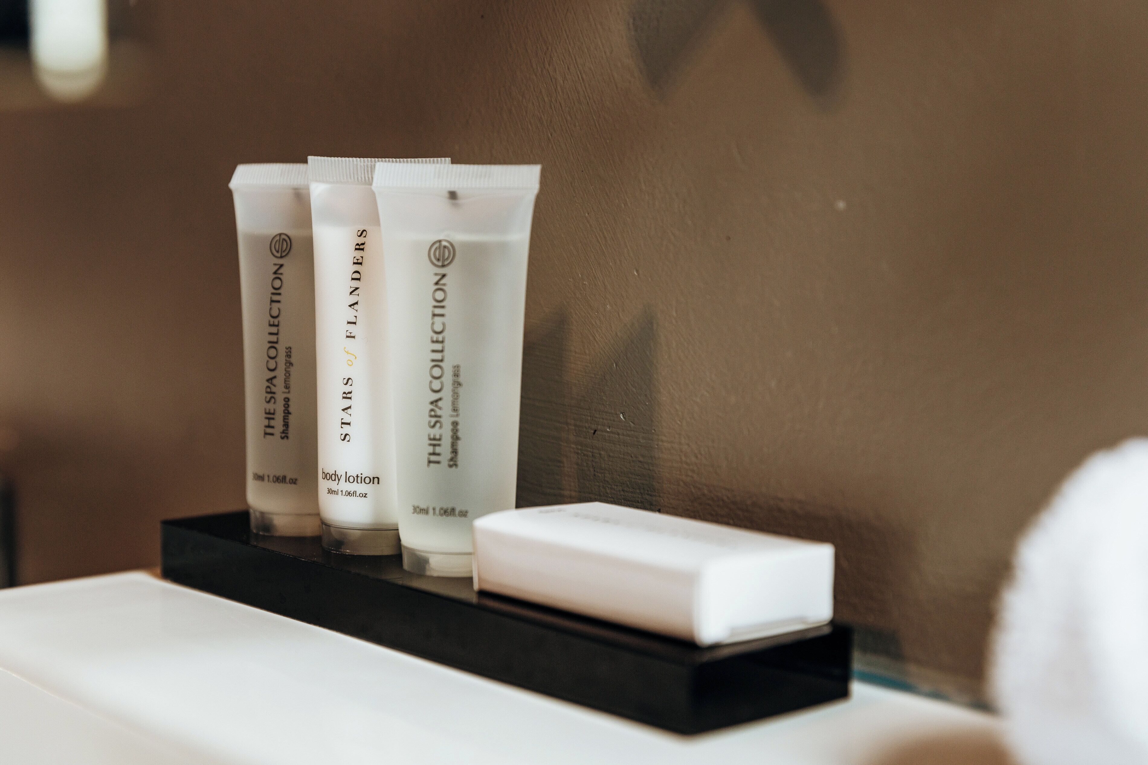 Three bottles of shampoo and conditioner on a black tray.