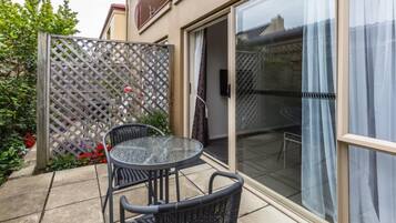 A patio with a glass door, two wicker chairs, and a small table.