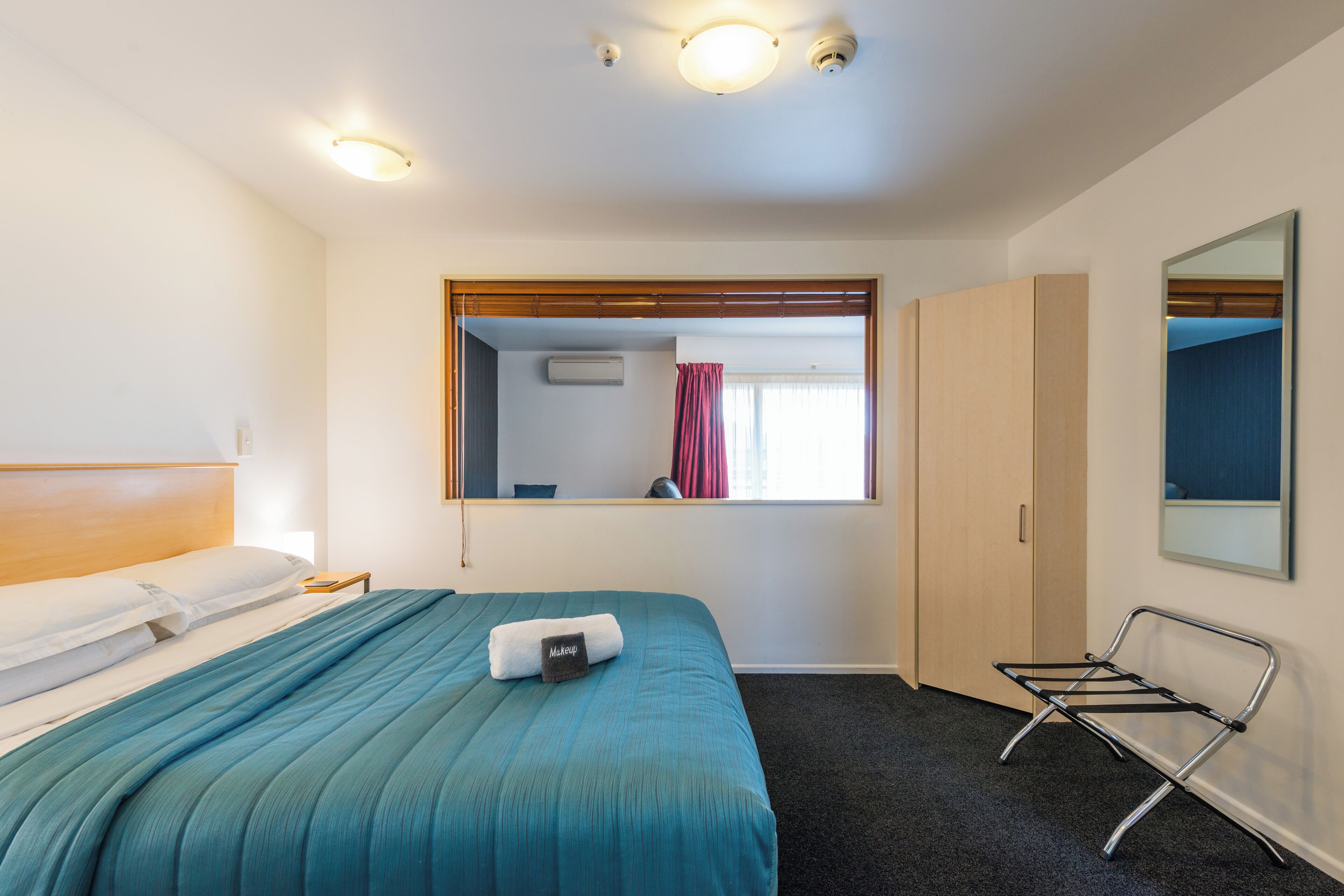 Una camera d'albergo con un letto, uno specchio, una finestra e un termosifone.