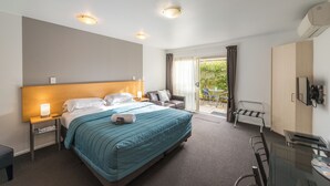 Ein Hotelzimmer mit Bett, Nachttisch, Lampe und Blick ins Freie.
