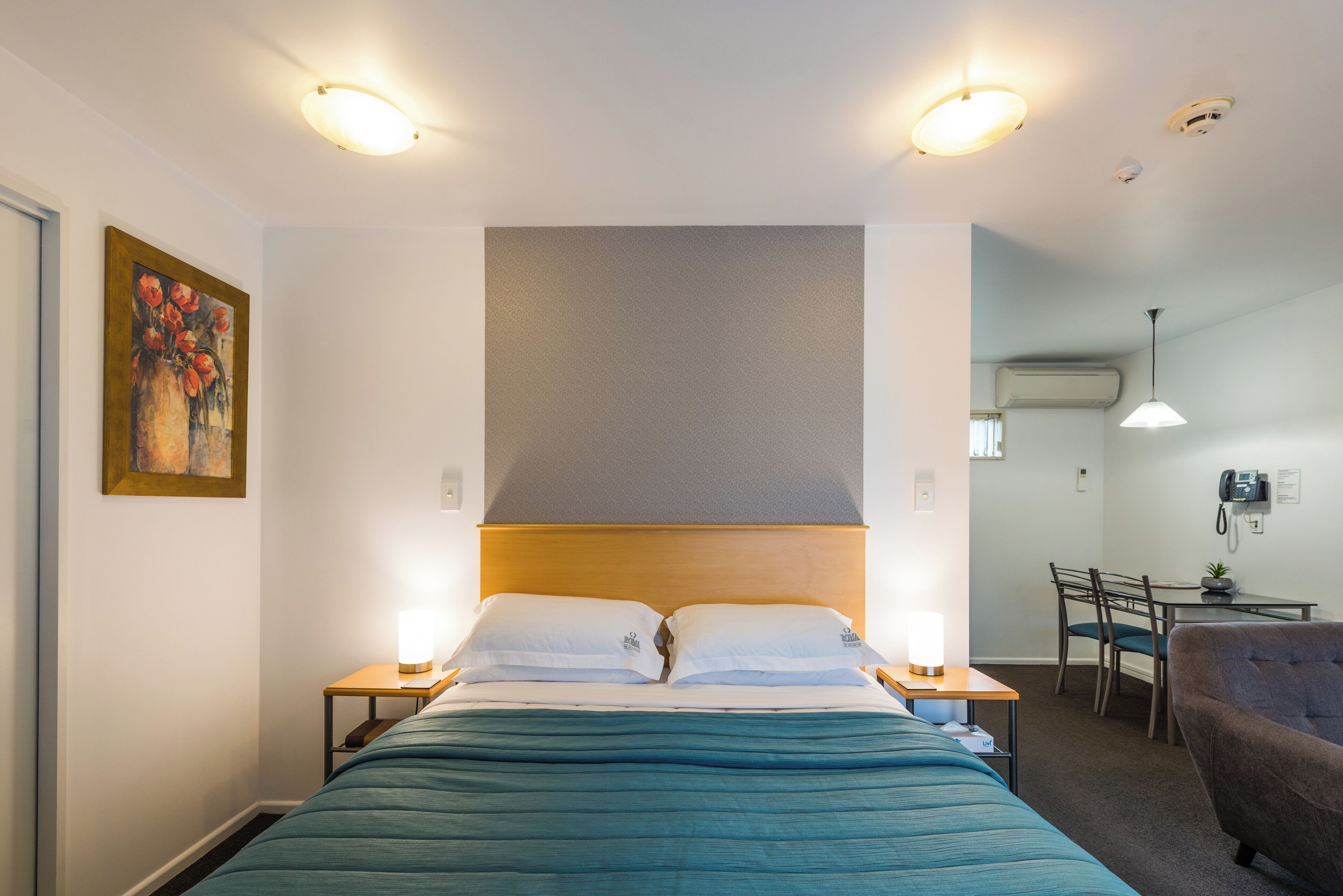 A hotel room with a bed, bedside tables, a desk, and a chair.