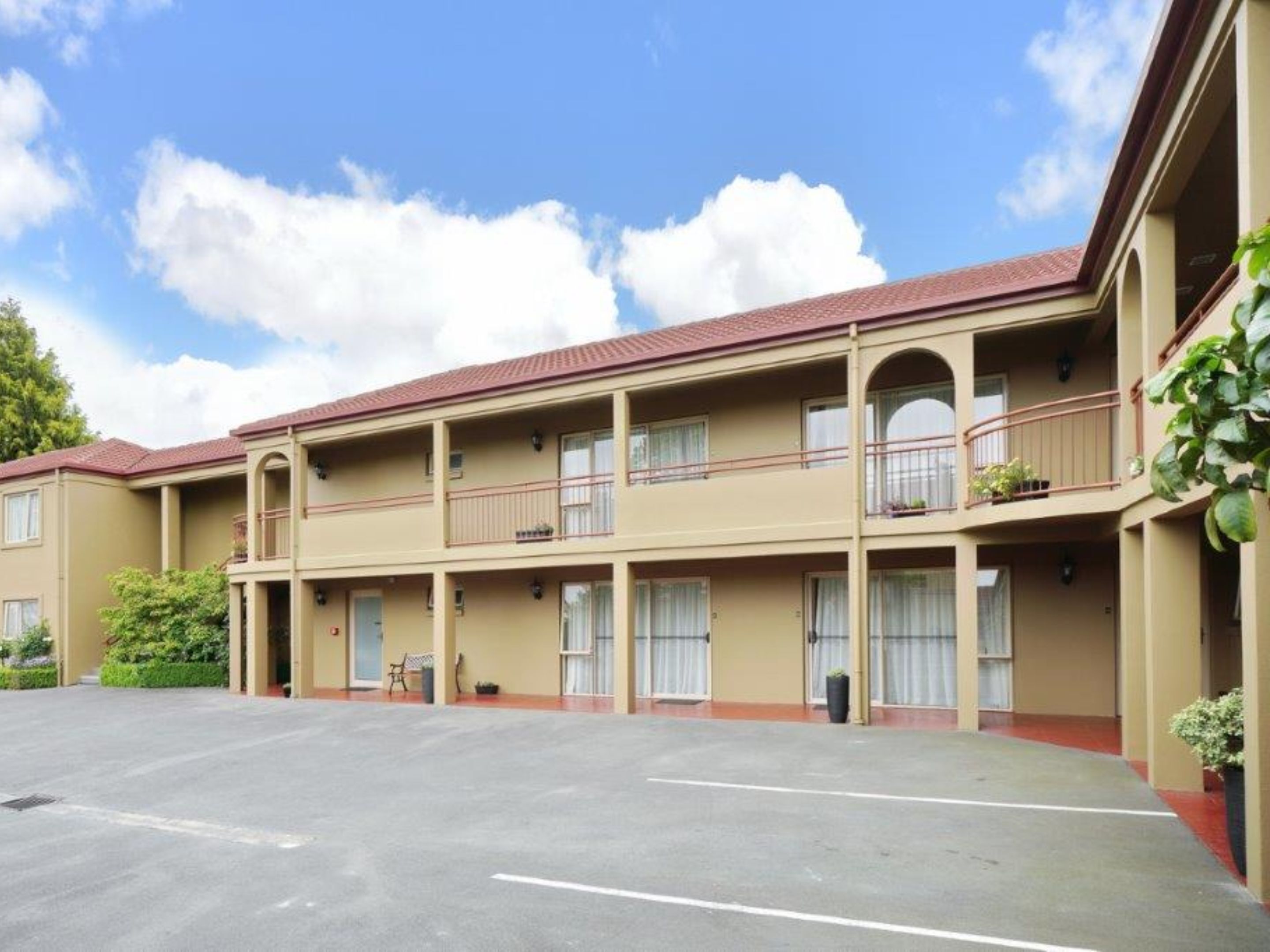A multi-story hotel with a central courtyard, balconies, and a parking lot.