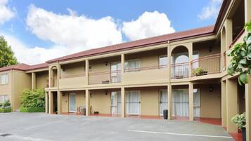A multi-story hotel with a central courtyard, balconies, and a parking lot.