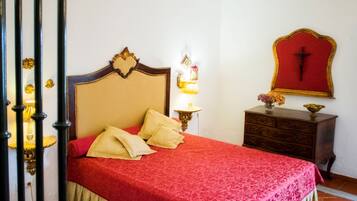 A bedroom with a bed, a nightstand, a lamp, and a wall-mounted cross.