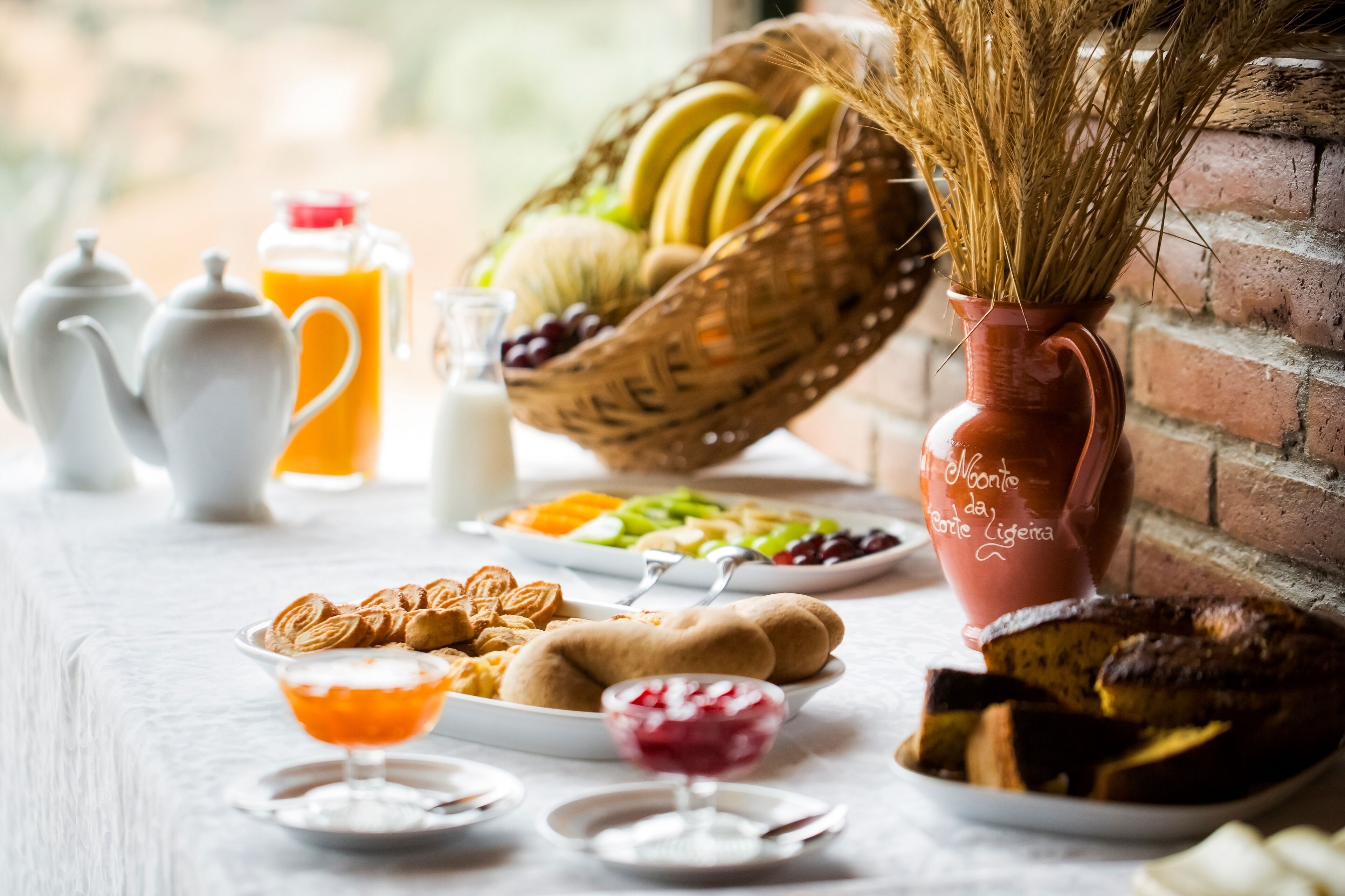 A breakfast setting with a variety of food items, including fruits, pastries, and beverages.