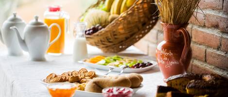 A breakfast setting with a variety of food items, including fruits, pastries, and beverages.