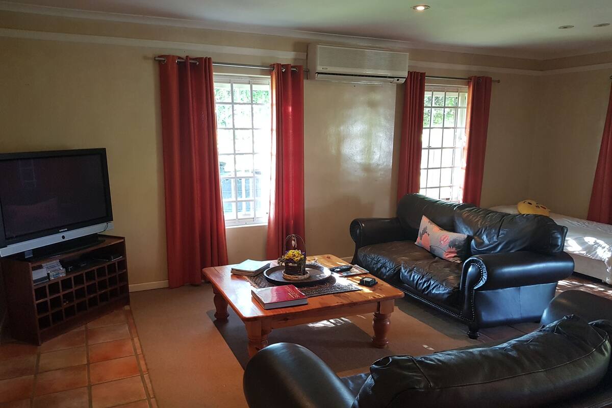 A living room with a television, a sofa, a coffee table, and a window with curtains.