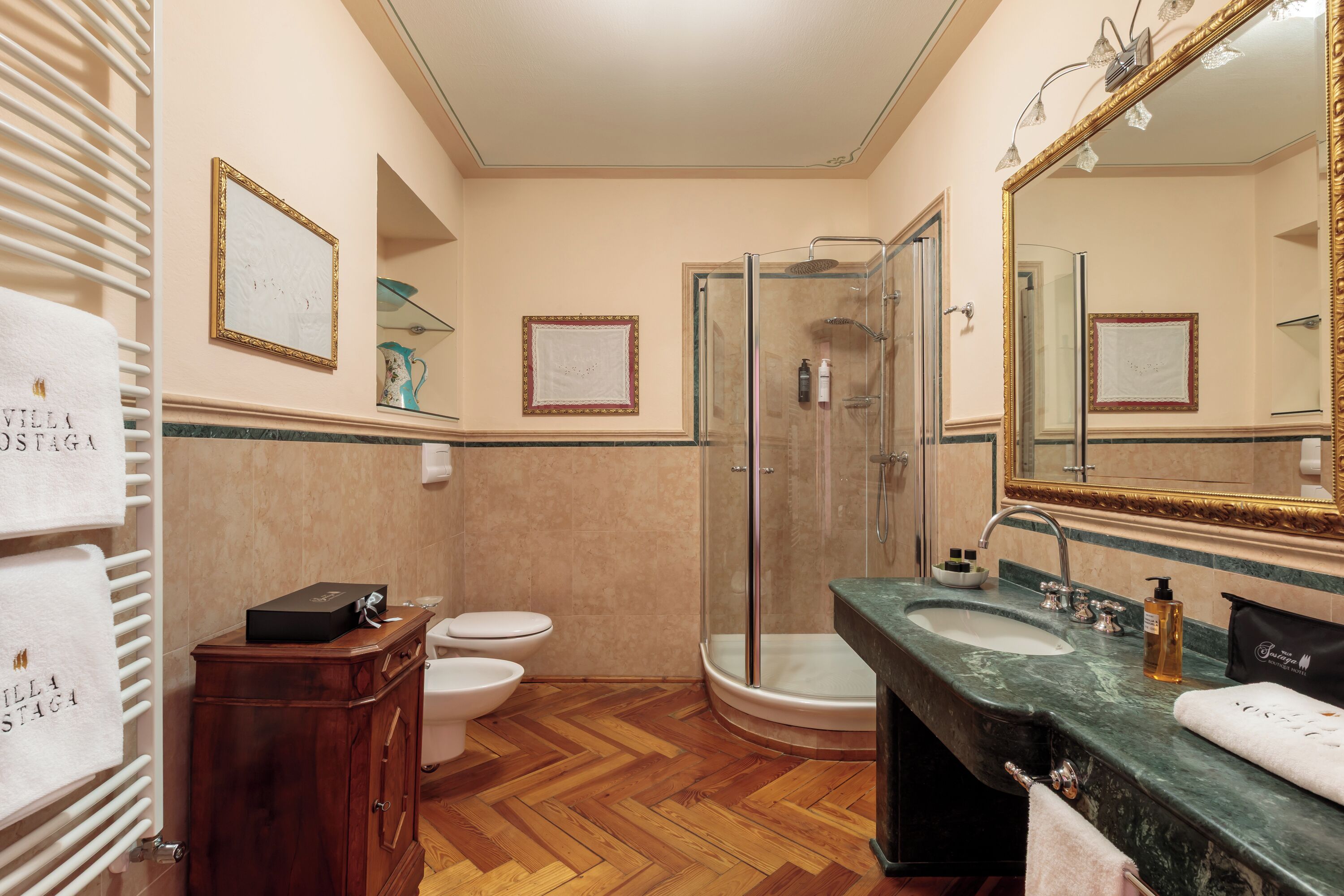 Un baño con suelo de madera, cabina de ducha de vidrio, lavabo de mármol y un espejo grande.